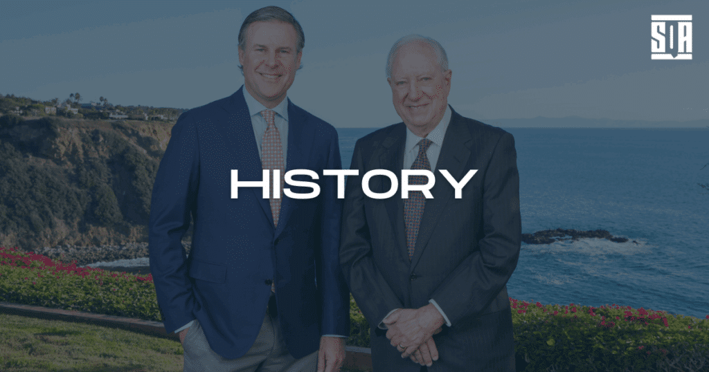 Two professionally dressed men standing in front of an ocean cliffside with the word "HISTORY" overlayed, representing SQA Services' company legacy.