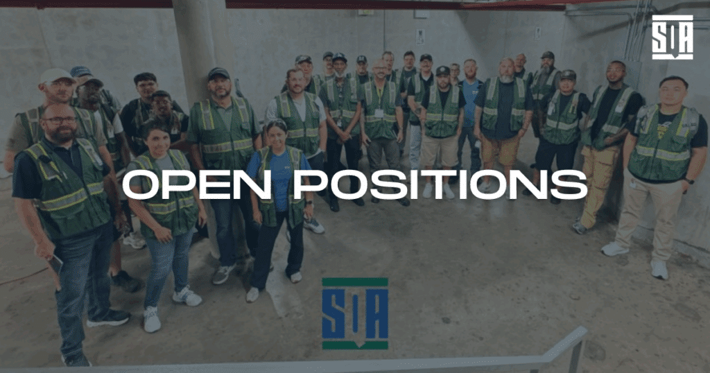 Group of SQA Services team members wearing safety vests standing together indoors with the words ‘Open Positions’ displayed across the image.